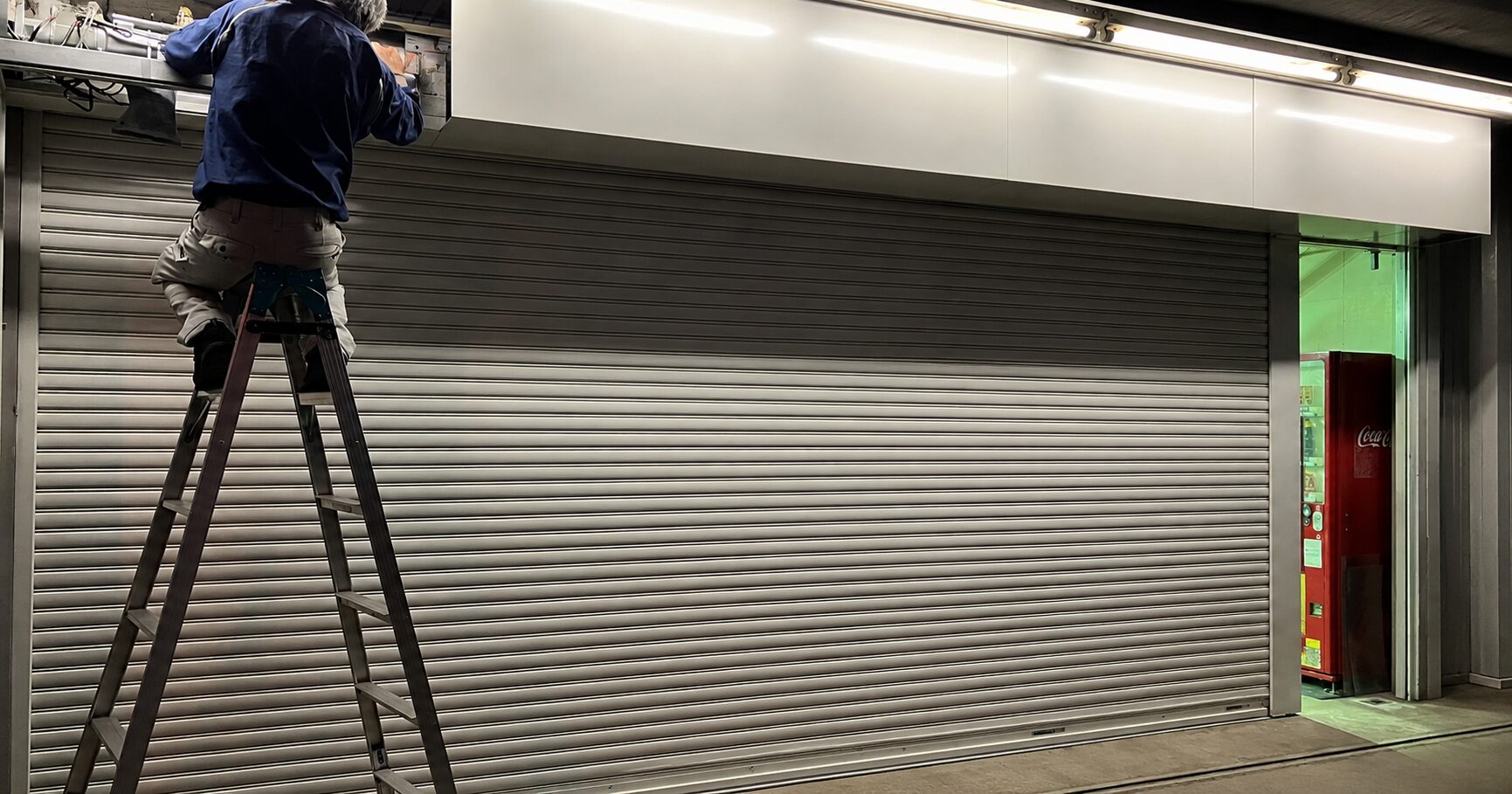 営業時間外に店舗のシャッター修理をしている写真